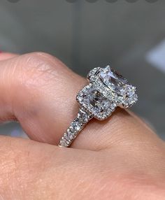 a woman's hand holding an engagement ring with two diamonds on top of it