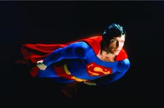 a man in a superman costume flying through the air with his hands on his hips