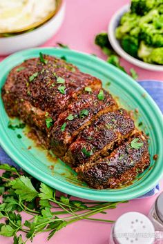 a meatloaf on a blue plate with broccoli and other foods in the background