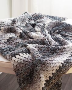 a crocheted blanket sitting on top of a wooden table next to a window