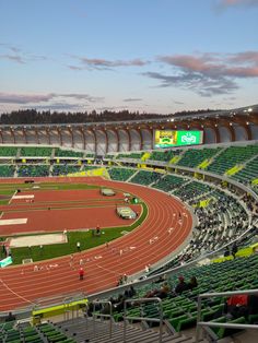 an empty stadium filled with lots of green seats and people standing on the sidelines