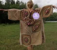 a woman in a crocheted robe is walking through the grass