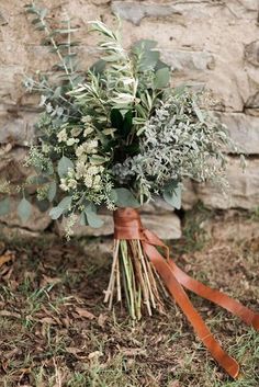 a bouquet of greenery tied to a stone wall