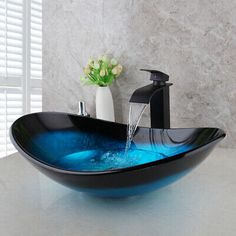 a black bowl shaped sink with blue water running from the faucet to it