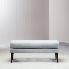 a light blue ottoman sitting on top of a white rug in front of a wall