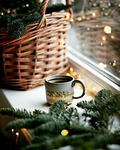 a cup sitting on top of a window sill next to a basket filled with christmas decorations