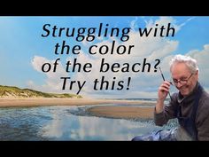 an older man is sitting on the beach talking on his cell phone and holding a stick