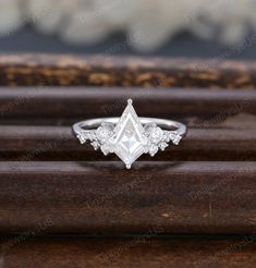 a white gold ring with diamonds on the top and bottom, sitting on a wooden surface