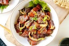 a bowl filled with meat and vegetables on top of a wooden cutting board