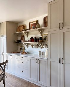 a kitchen with white cabinets and shelves filled with dishes on top of it's counters