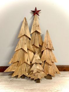 three wooden christmas trees sitting next to each other on the floor in front of a wall