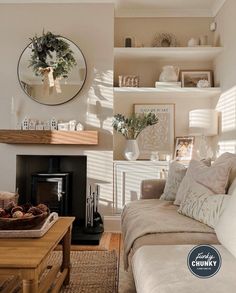 A cosy cottage living room full of gorgeous neutral tones. To the right of the image there is a side view of a sofa, which has been decorated with plenty of throws and accessories. To right left of the image, there is a log burner which has been finished perfectly with one of our solid oak mantel beams. Hydra Facial, Roast Dinner, Neutral Living Room