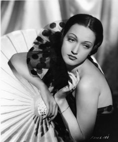 an old black and white photo of a woman in a dress holding a parasol