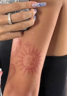 a woman's arm with sun and moon tattoos on her left arm, while she is wearing a ring