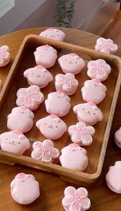 there are many pink cookies in the shape of teddy bears on a wooden tray with flowers