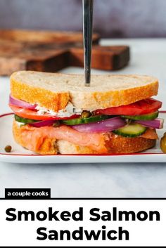 a grilled salmon sandwich on a white plate with a knife stuck in the middle