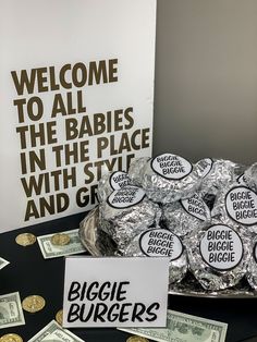 a table topped with lots of money next to a sign that reads welcome to all the babies in the place with style and grace