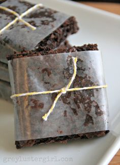 three pieces of chocolate brownie on a white plate with yellow twine around the edges