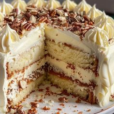 a cake with white frosting and pecans is cut in half on a plate