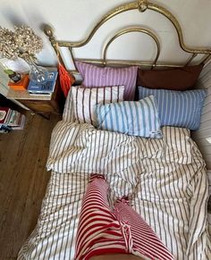 an unmade bed with striped sheets and pillows