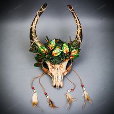 an animal skull with flowers on it's head and feathers attached to the horns