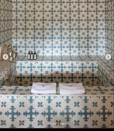 a bathroom with blue and white tiles on the walls, two towels folded in front of the bathtub