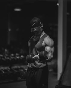 black and white photograph of a man wearing a helmet, holding a pair of dumbbells