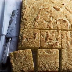 sliced squares of cake sitting on top of a cutting board next to a knife and fork