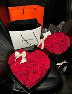 two large heart shaped roses are sitting on a black leather chair next to shopping bags