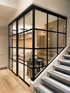 a staircase with glass walls leading up to the living room and dining area in this modern home