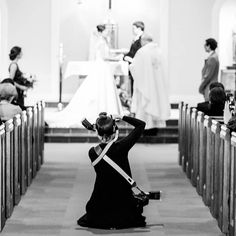 a woman kneeling on the ground in front of pews with other people standing behind her