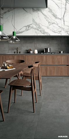 a modern kitchen with marble counter tops and wooden chairs around a table that has food on it