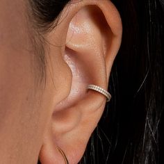 a close up view of a woman's ear wearing a pair of diamond hoop earrings