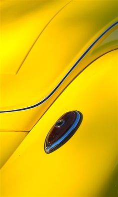 the front end of an old yellow car with chrome trim and door handle on it