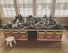 a child playing with a train set in a play room filled with furniture and windows