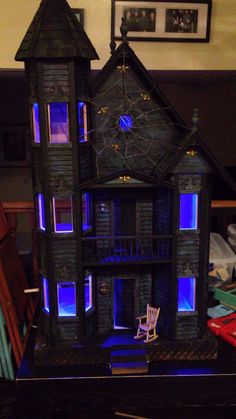 a doll house is lit up with blue lights on the windows and in the front