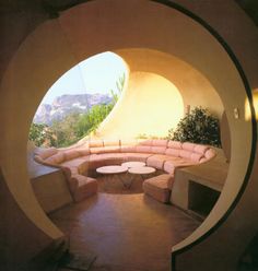 a living room filled with lots of furniture under a large round window on the side of a building