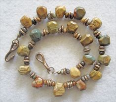 Miriam designed this elegant necklace using Owyhee Oregon Picture Jasper. Each stone shows its natural rustic characteristics, with a different pattern of the soft earthy colors of clay, teal, sage, brick, and sand. Miriam blended these gently faceted nuggets with mixed jasper and agate roundelles, and bronze, to add an attractive and unique touch to this necklace. Suitable for men and women. -The full length of the necklace is 17 inches, including the beautiful bronze clasp.  - The Oregon Jaspe Artisan Brown Single Strand Jewelry, Fire Jewelry, Jasper Jewelry, Ceramic Necklace, Bronze Necklace, Jasper Necklace, Beading Ideas, Garnet Necklace, Locket Charms