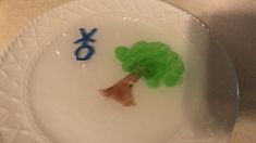 a white plate topped with a green tree and the word xo painted on it