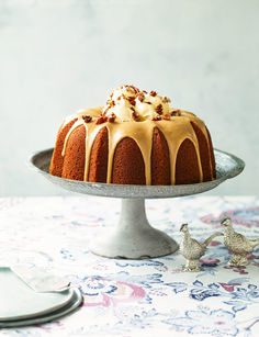 a bundt cake with icing and nuts on top, sitting on a plate