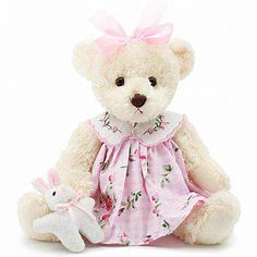 a white teddy bear wearing a pink dress and holding a small stuffed animal in it's lap