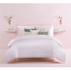 a white bed with pink walls and pillows