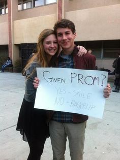 a man and woman standing next to each other holding a sign that says given prom