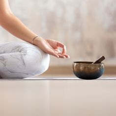 a woman sitting on the floor in front of a bowl and spoon with her hands