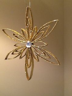 a gold ornament hanging from the ceiling in a room with a white wall