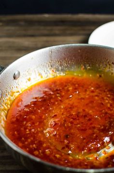 a pan filled with sauce on top of a wooden table