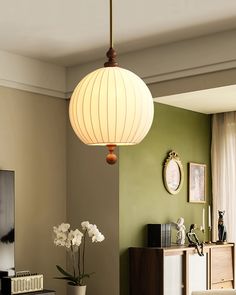 a living room filled with furniture and a large white ball light hanging from the ceiling