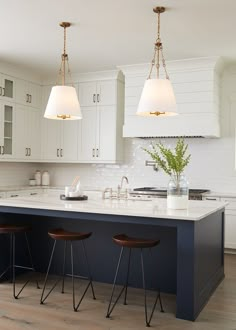 two lights hanging over a kitchen island with stools