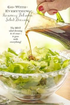 a woman pouring dressing into a salad in a glass bowl on top of a table