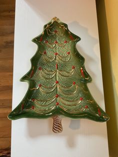 a green ceramic christmas tree ornament hanging on a wall